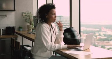 Pensive serious african woman sit indoor working using laptop
