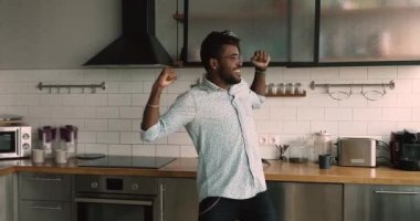 Carefree lively african guy dance in domestic kitchen