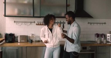 Lively happy african couple dancing in modern kitchen