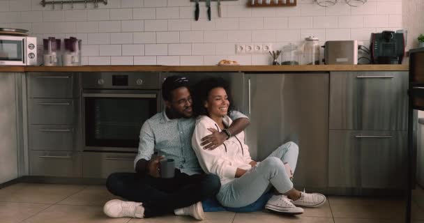 Relaxed african couple daydreaming sitting on floor in modern kitchen — Αρχείο Βίντεο