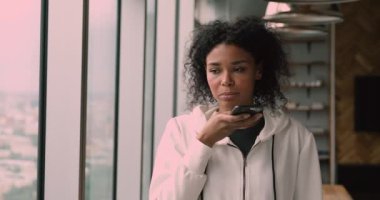 Akıllı telefon tutan Afrikalı kadın hoparlörden telefona cevap veriyor.