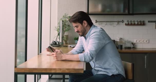 Man sit at bar counter in kitchen resting using smartphone — Stock Video