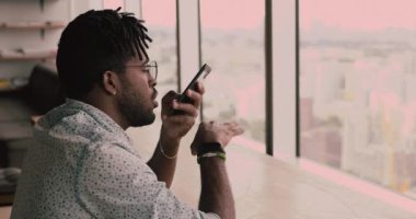 Akıllı telefonu tutan Afrikalı adam hoparlörden konuşuyor.