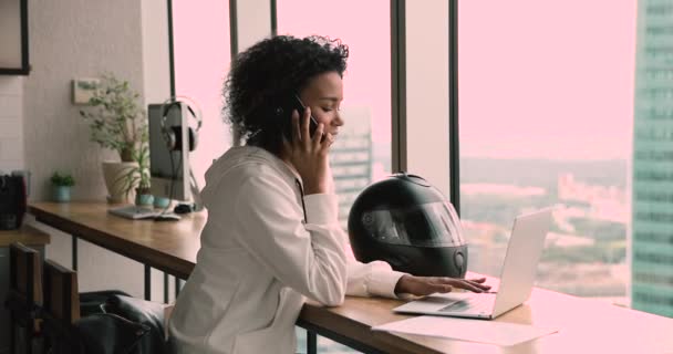 Mulher africana mensagens de texto no laptop enquanto conversa no telefone inteligente — Vídeo de Stock