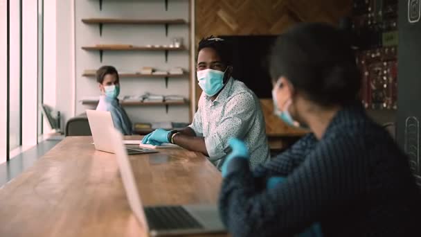 Multiethnische Mitarbeiter mit Gesichtsmasken und Handschuhen halten am Arbeitsplatz Abstand — Stockvideo