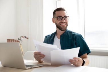 Gülümseyen erkek çalışanlar laptopta iş arkadaşlarıyla konuşuyor.