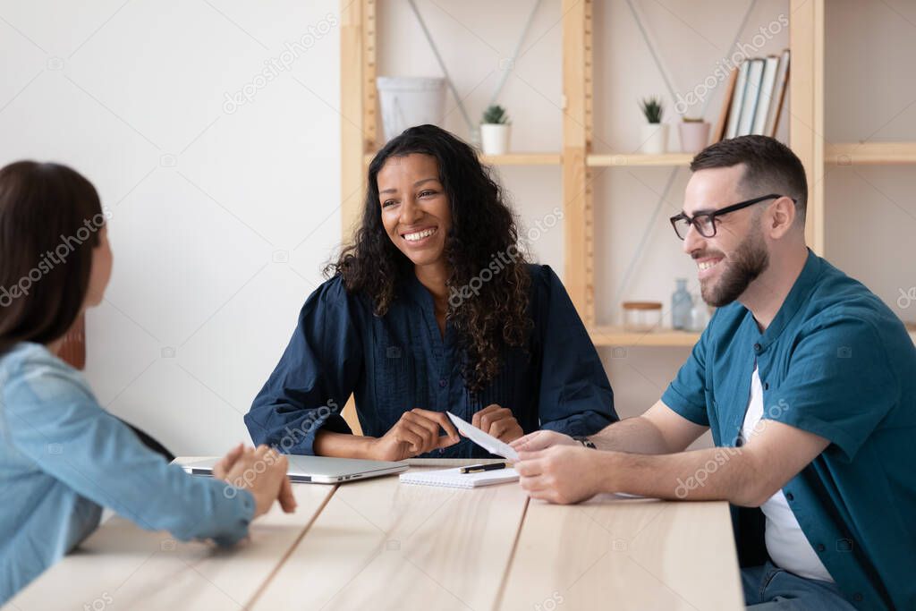 Smiling employers interview female job candidate at meeting