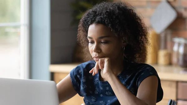 Thoughtful young african american woman working on computer.