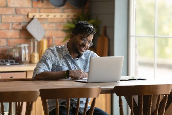 Feliz joven hombre de raza mixta disfrutando de aprender a distancia. — Foto de Stock