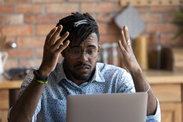 Confused young african american man reading email with bad news.