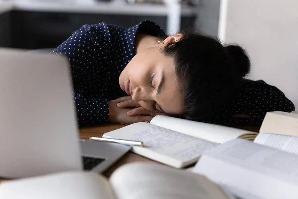 Lelah muda ras campuran wanita tidur di tempat kerja di antara buku-buku — Stok Foto