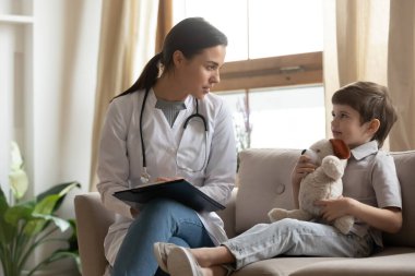 Kadın doktor konuşması klinikteki küçük çocuğu muayene ediyor.