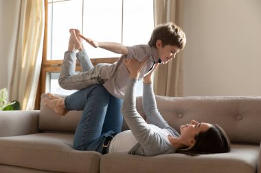 Mutlu anne küçük oğluyla oturma odasında oynuyor.