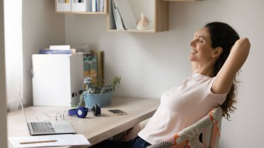 Gülümseyen, gevşeyen, rahat bir sandalyede uzanan bir kadın.