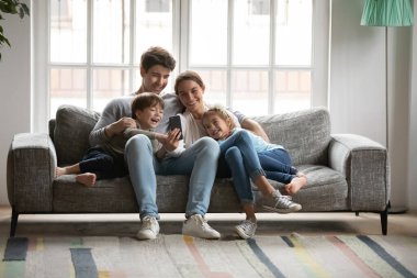 Cep telefonu kullanan iki çocuklu mutlu bir aile..