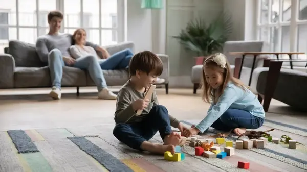 Feliz adorável crianças brincando de brinquedos enquanto os pais relaxam. — Fotografia de Stock