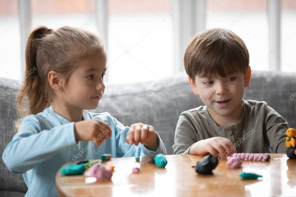 Joyful two cute little preschool children playing with playdough.