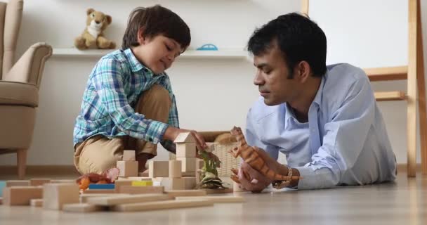 Indiska pappa och son leker med dinosaurier leksaker och tegelstenar — Stockvideo