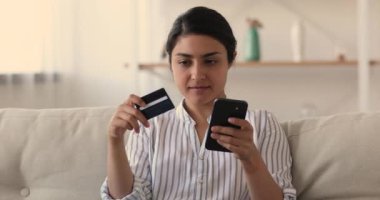Hintli kadın internet üzerinden akıllı telefon ve kredi kartı kullanarak alışveriş yapıyor.