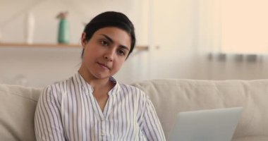 Laptopta çalışan düşünceli Hintli kadın kapalı alanda iş yapıyor.