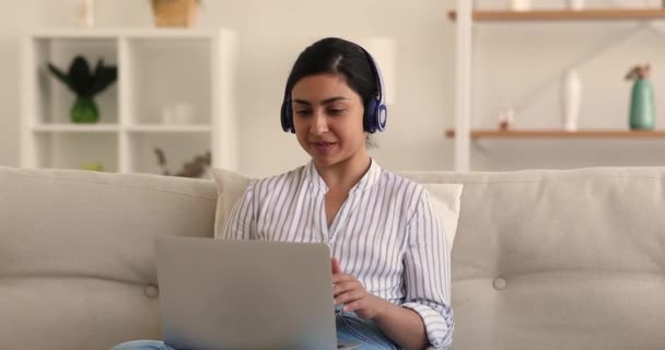 Mulher em fones de ouvido se comunica usando videoconferência e laptop — Vídeo de Stock