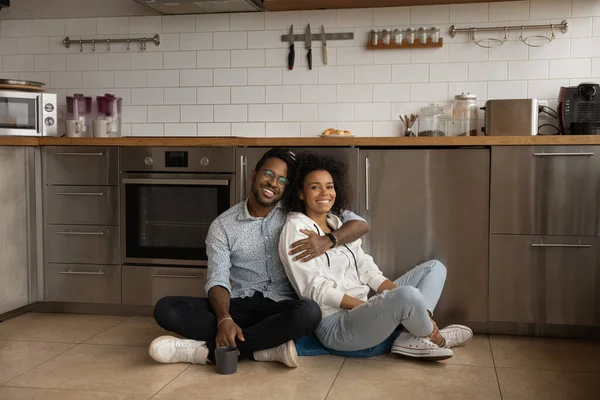 Retrato de sorridente casal biracial locatários relaxar na cozinha — Fotografia de Stock