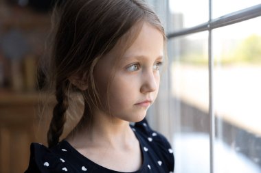 Üzgün, düşünceli, pencereden dışarı bakan küçük kızı kapat.