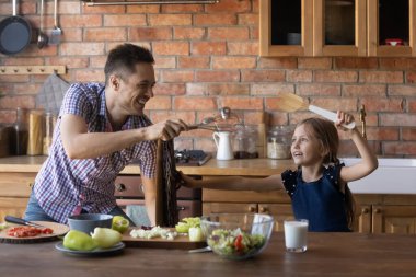 Mutlu baba ve küçük kız mutfakta oyuncaklarla oynuyorlar.