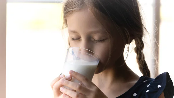 De cerca linda niña bebiendo leche, sosteniendo el vidrio —  Fotos de Stock