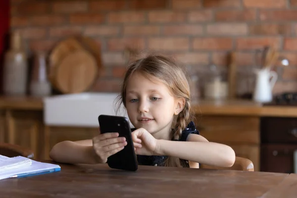 Fermer la petite fille en utilisant le téléphone à la maison, applications de navigation — Photo