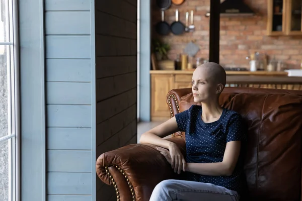 Thoughtful hairless sick woman sitting in armchair, looking in distance — 图库照片