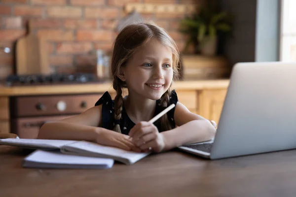 Smiling little girl watching online lesson, writing notes, homeschooling concept — Stock Photo, Image