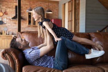 Gülen baba evdeki kanepede kızıyla oynuyor.