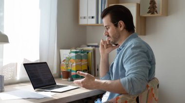 Kendine güvenen iş adamı telefonda konuşuyor, ortağıyla görüşüyor, dizüstü bilgisayar kullanıyor.