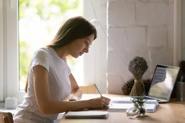 Vedere laterală focalizată femeie studiind, folosind laptop, scriind note — Fotografie, imagine de stoc