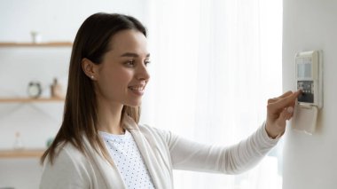 Akıllı ev sisteminde düğmelere basan gülümseyen genç kadın