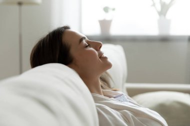 Gülümseyen genç kadın arkana yaslan ve rahat kanepeye uzan.