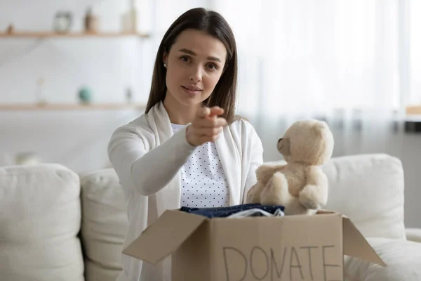 Young woman holding donation box, pointing finger at you — Stock Photo, Image