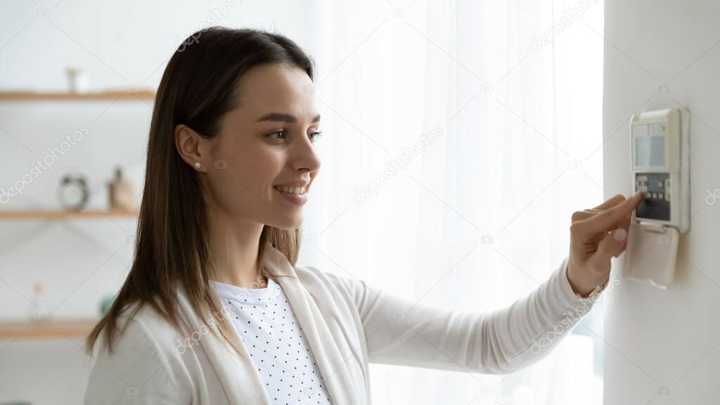 Smiling young woman pressing buttons on smart house system