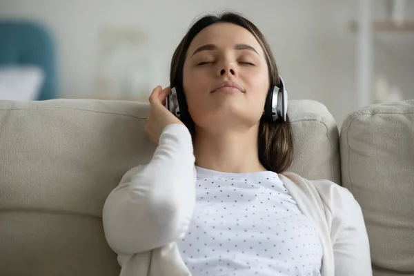 Gros plan jeune femme paisible portant des écouteurs jouissant de la musique — Photo