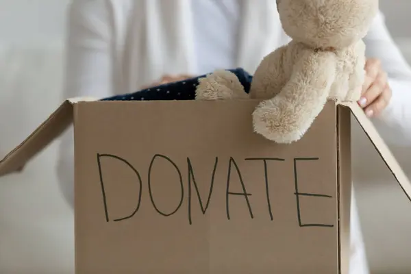 Close up woman holding donation box with clothing and toys — Stock Photo, Image