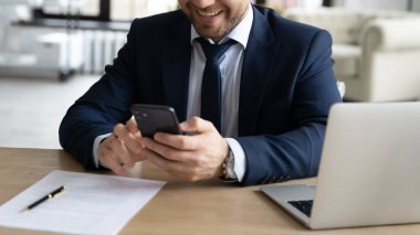 Akıllı telefon kullanarak, masada oturarak başarılı gülümseyen iş adamını kapat.