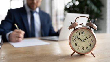 Masadaki çalar saati kapat, iş adamı arka planda çalışıyor.