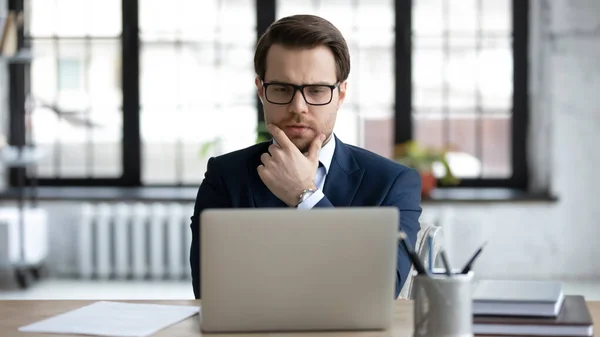 Close up thoughtful businessman wearing glasses pondering project strategy