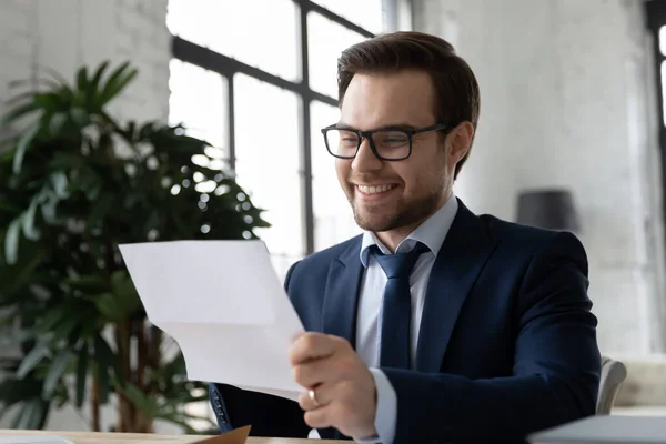 Close up smiling satisfied businessman wearing glasses reading letter — Stock Photo, Image