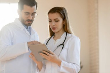 Çeşitli doktorlar hasta bilgilerini birlikte tartışmak için tablet kullanıyorlar.