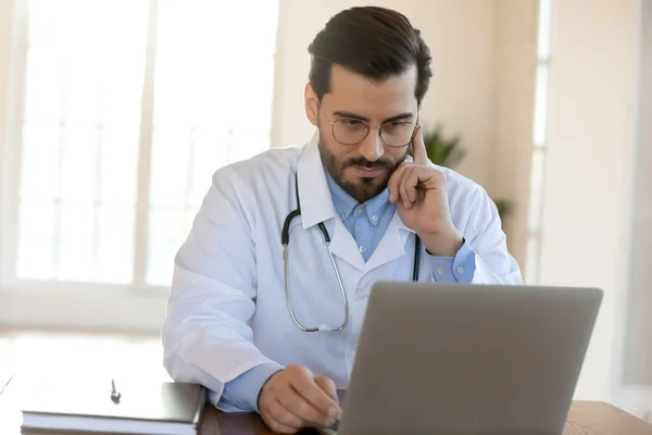 Pensiv manlig läkare arbetar med datortänkande — Stockfoto