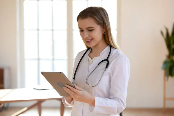 Glimlachende vrouwelijke arts gebruikt tablet in moderne kliniek — Stockfoto