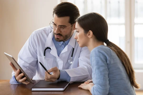 Mužský lékař vysvětlit výsledky na tabletu pacientce — Stock fotografie
