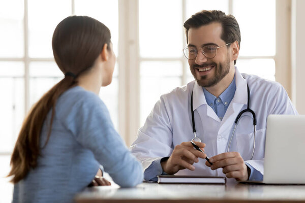 Smiling male doctor consult female patient in clinic